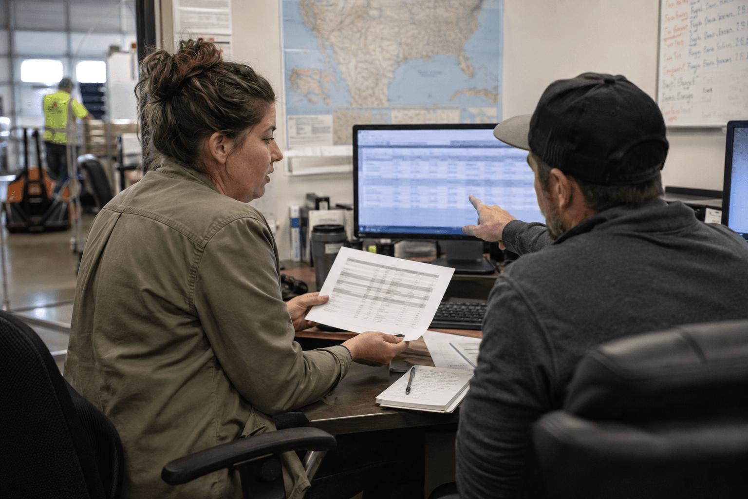 Two logistics professionals reviewing organized freight rates at an operations workstation